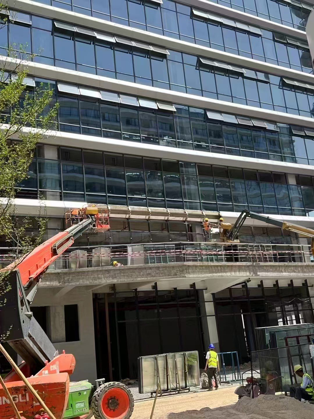 real aluminum facade panel installation site with workers and lifting equipment