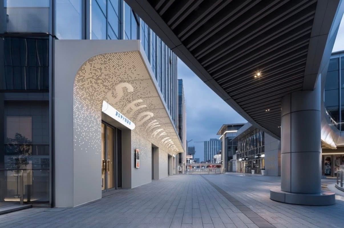 Curved entrance canopy clad with artistic perforated aluminum panels and integrated lighting