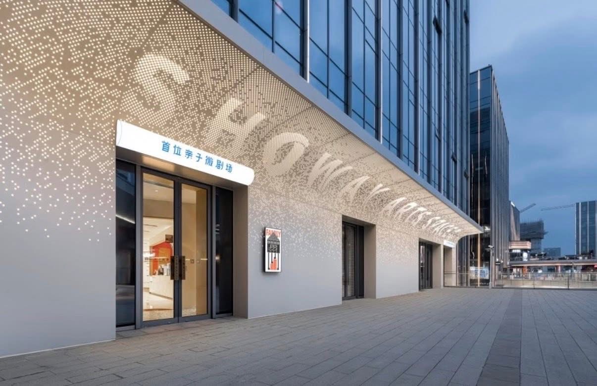 Street level commercial entrance with curved perforated aluminum canopy and wall panels