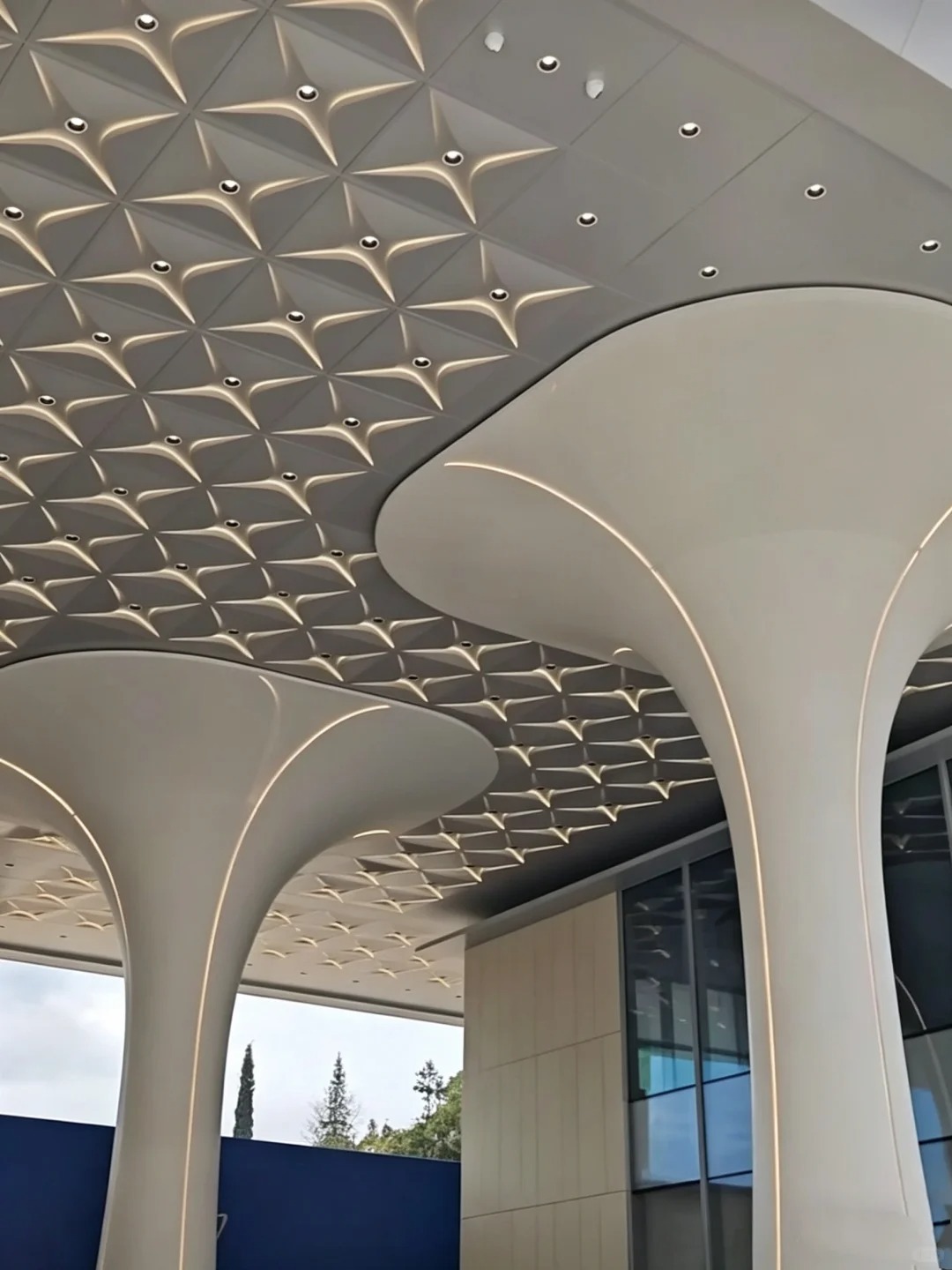 Custom double curved aluminum ceiling panels with integrated linear lighting and formed aluminum columns