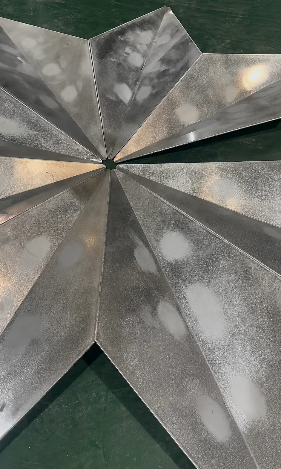Close view of unfinished 2.5 mm folded solid aluminum modules meeting at the central joint during workshop fit-up.