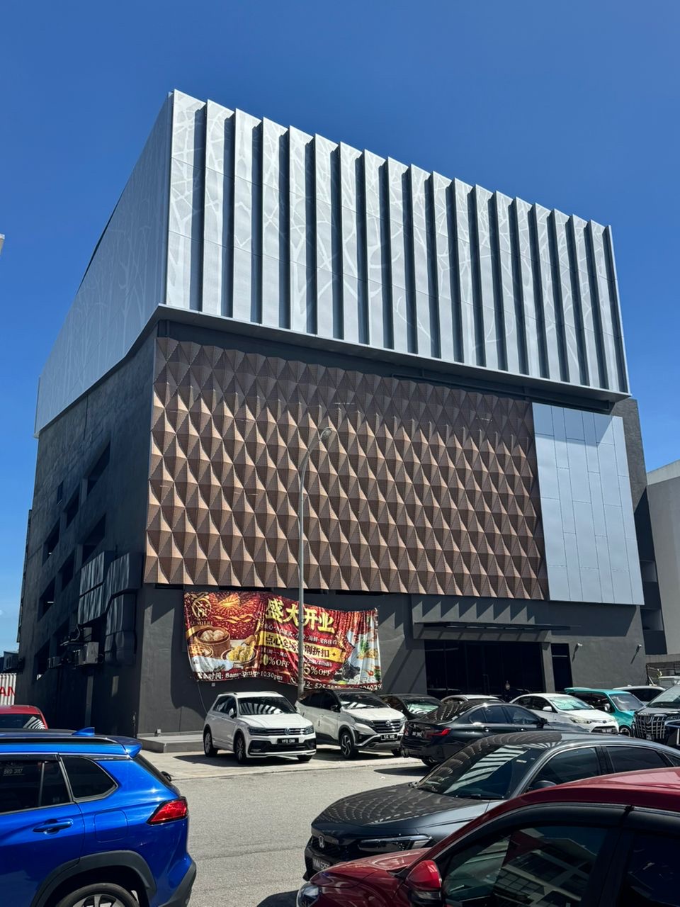 Completed Malaysia hotel facade with Punchuk solid aluminum panels, silver vertical aluminum fins and bronze geometric perforated aluminum screen panels