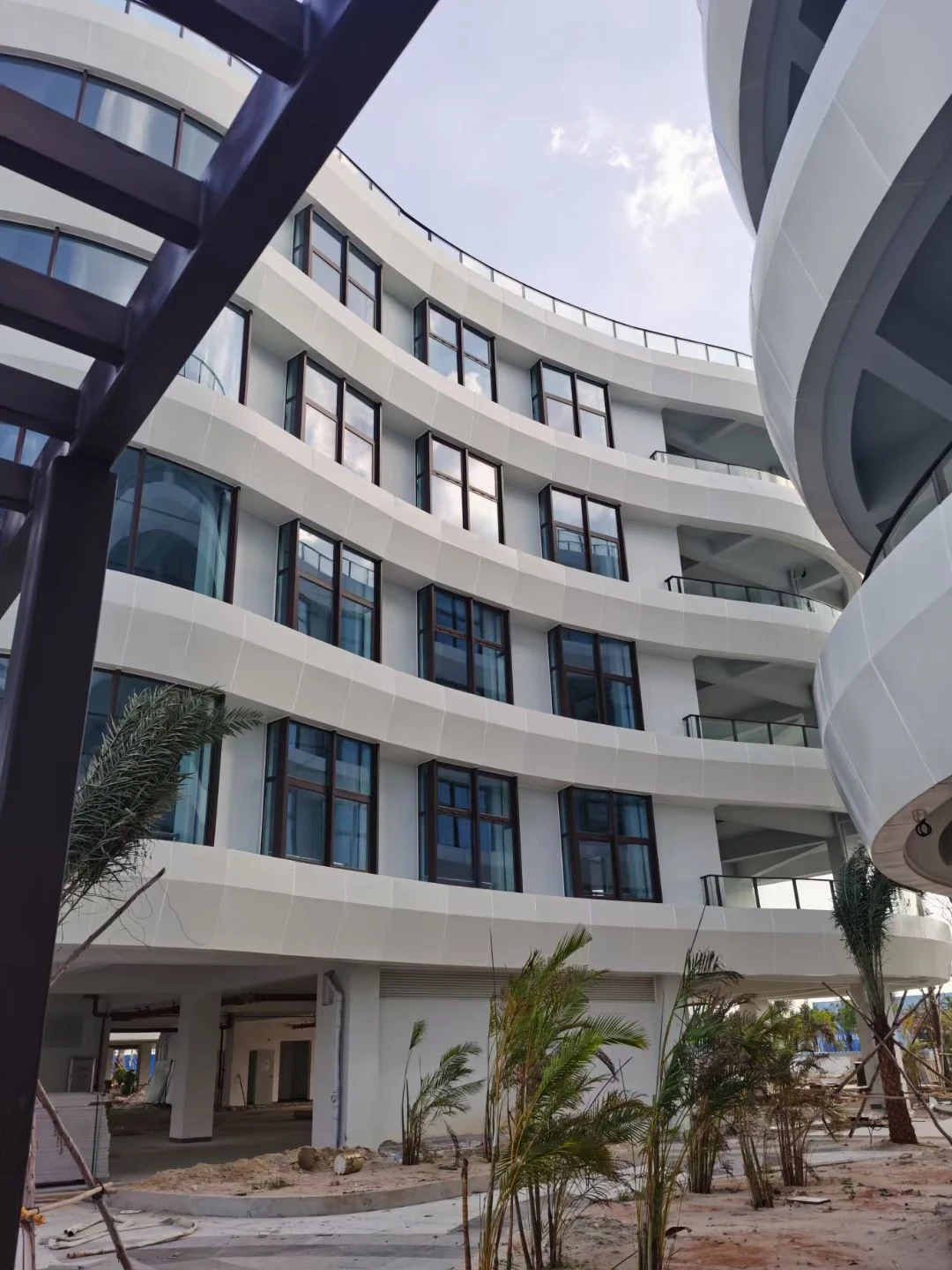 White curved solid aluminum cladding wrapping an inner courtyard facade around dark-framed windows