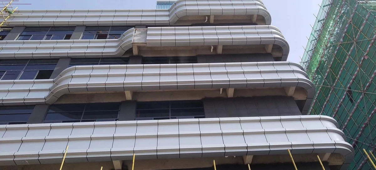 Close-up of curved white solid aluminum panels around projecting facade edges and panel joints