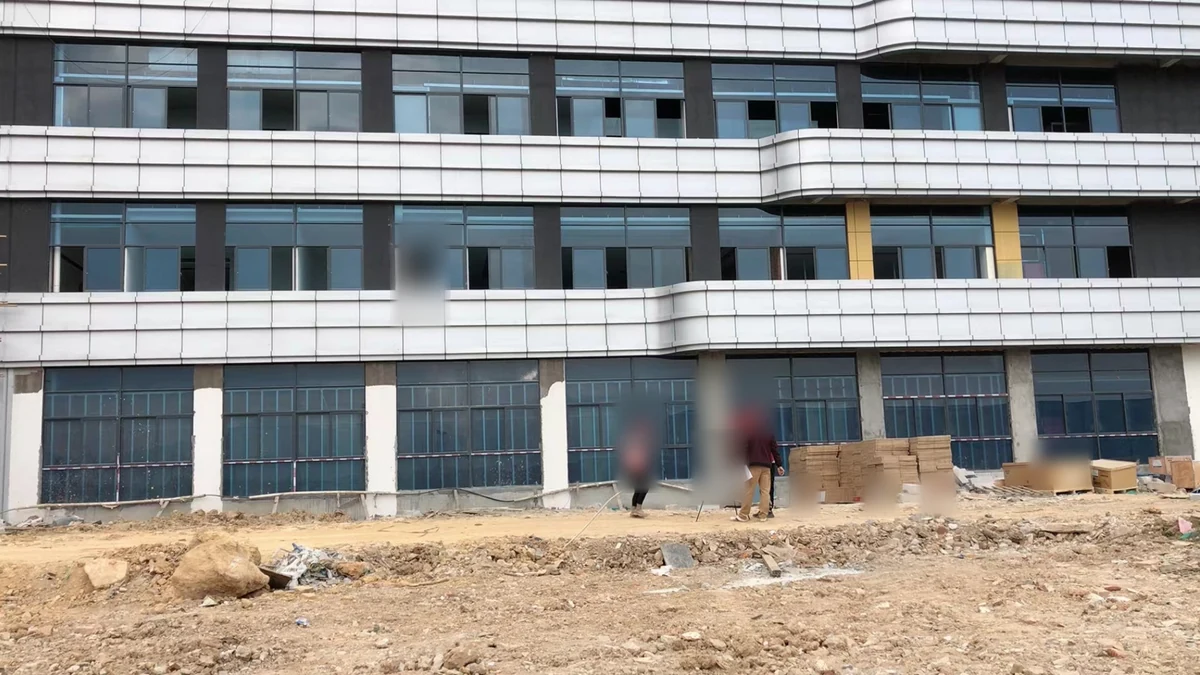 Site measurement activity beside white solid aluminum panels across a multi-storey facade