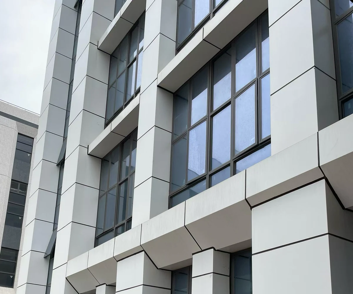 White solid aluminum panel returns around tall window openings and facade columns