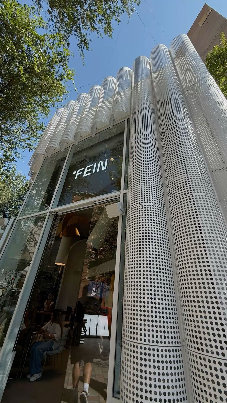 White curved perforated aluminum screen used as a storefront facade feature